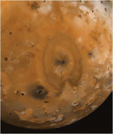 FIGURE 7.5 Jupiter’s moon Io. The large heart-shaped pattern is the deposit of a volcanic plume erupting at its center. The many black features are volcanic calderas. SOURCE: Courtesy of NASA/JPL.