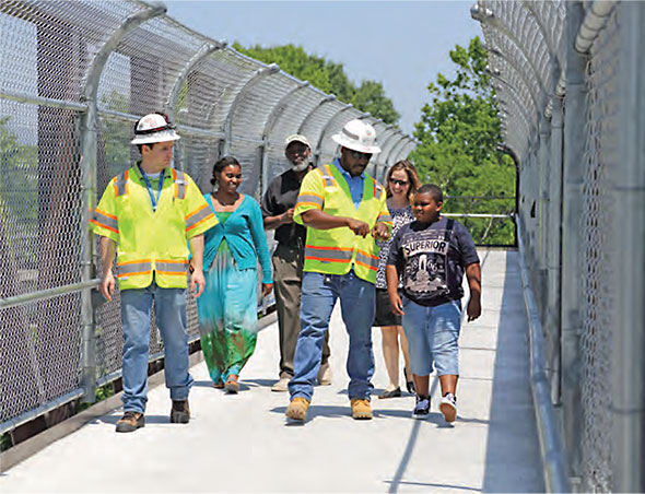 Elementary school students and Virginia Department of Transportation engineers tour a new pedestrian bridge over I-264 in Portsmouth. HCM6 includes tools to assess pedestrian facilities and other designs for nonautomobile modes.